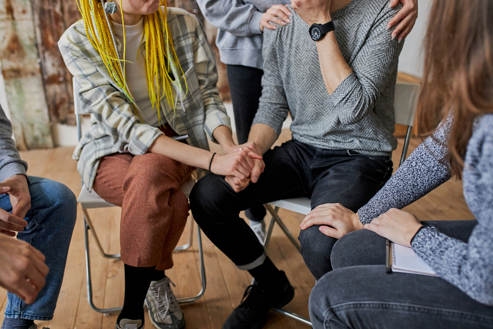 Group of recovering addicts spend time comforting a man who is struggling with substance abuse