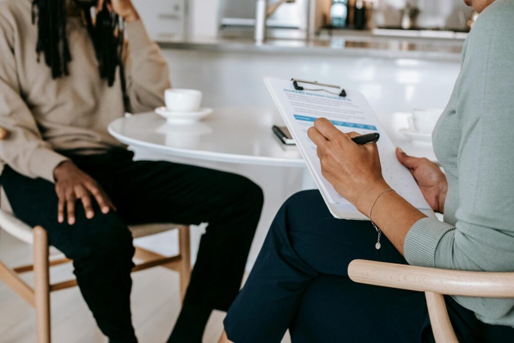 Counselor taking notes while meeting with a mental health client coverged by Aetna mental health rehab plans